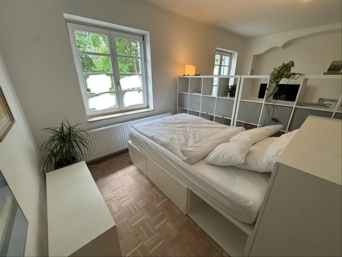 Double bed with room-divider shelving and pendant lamp