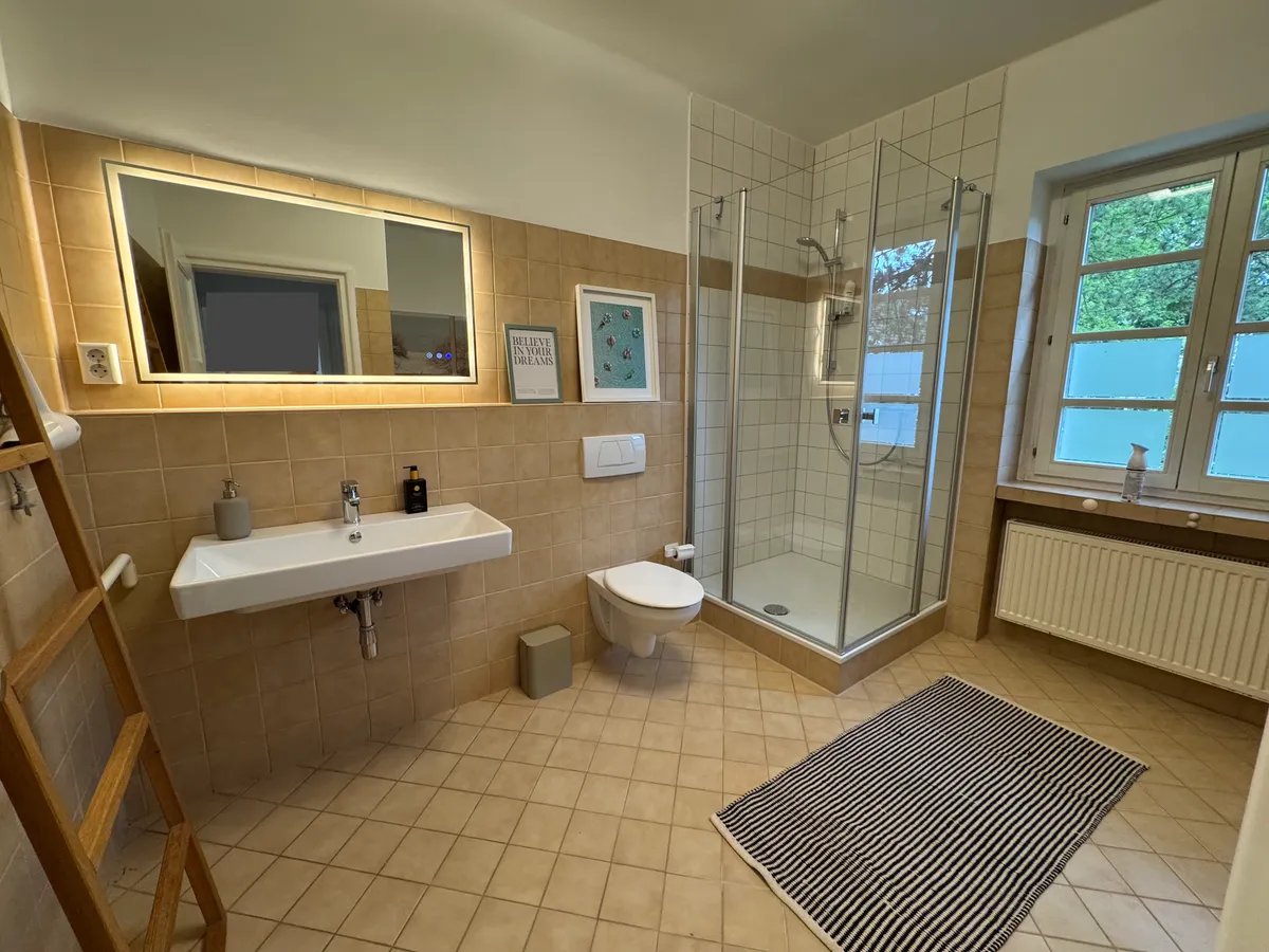 Bathroom vanity with backlit mirror and shower cabin